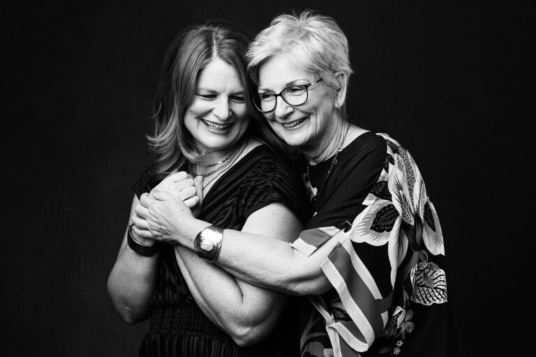 Black and white photograph of a daughter sharing a laugh with her mother during a professional photo session.