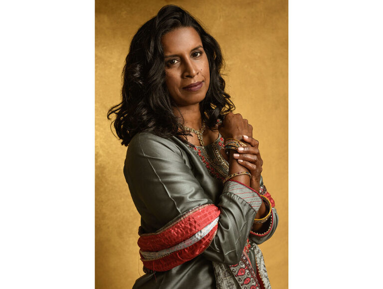 A confident and strong Indian woman looks powerful as she adjusts her bracelets and engages with the viewer.