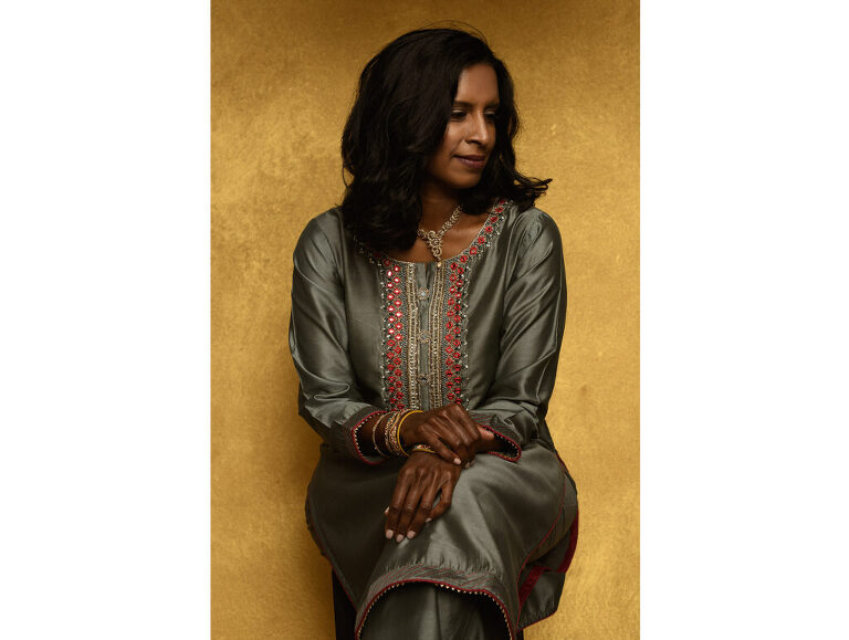 Legacy portrait of an Indian woman wearing a sherwani against a gold backdrop.